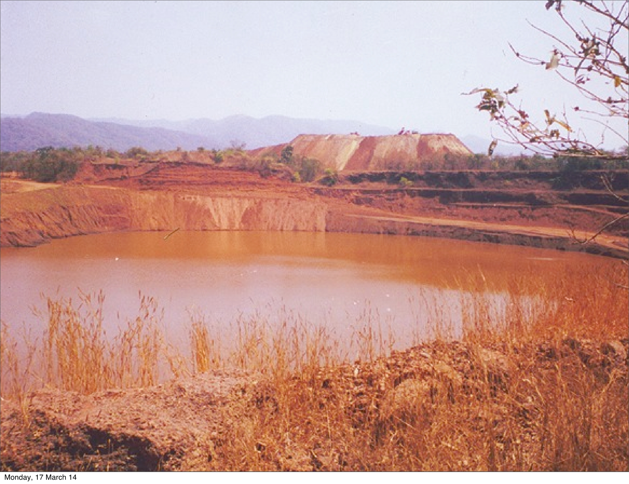 Mining dump in the background, red polluted water in the foreground